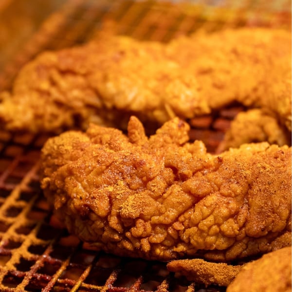 Close-up of Sumah Hot Chicken's crispy, golden-brown fried chicken tenders, heavily seasoned with spices.